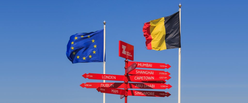 Drapeaux de l'Union européenne et de la Belgique encadrant un panneau indicateur maritime